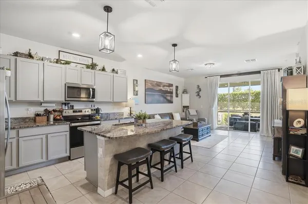 a large kitchen with cabinets chairs and stainless steel appliances