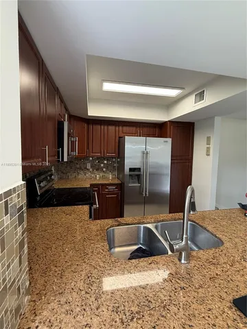 a kitchen with stainless steel appliances granite countertop a sink and a refrigerator