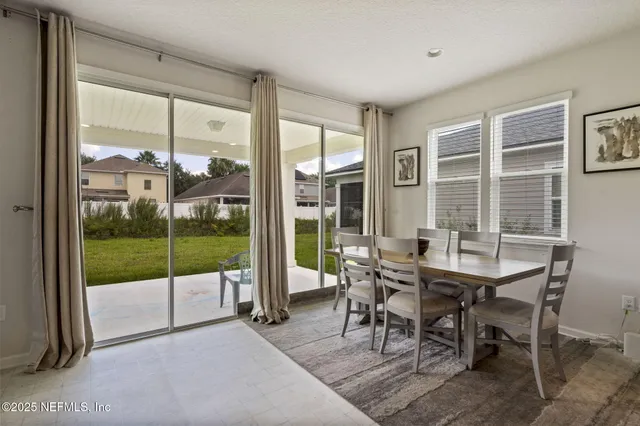 a dining room with furniture and large windows