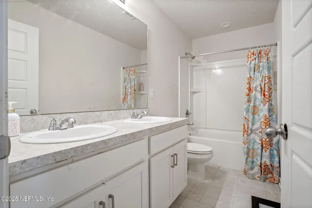a bathroom with a double vanity sink toilet mirror and shower
