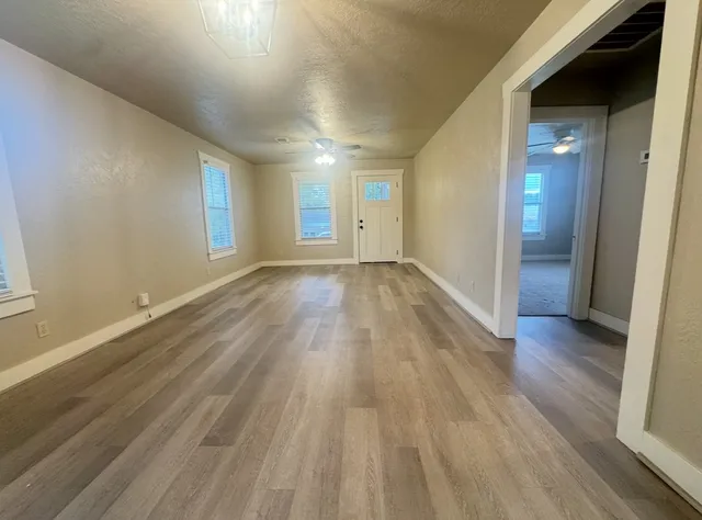 an empty room with wooden floor and windows
