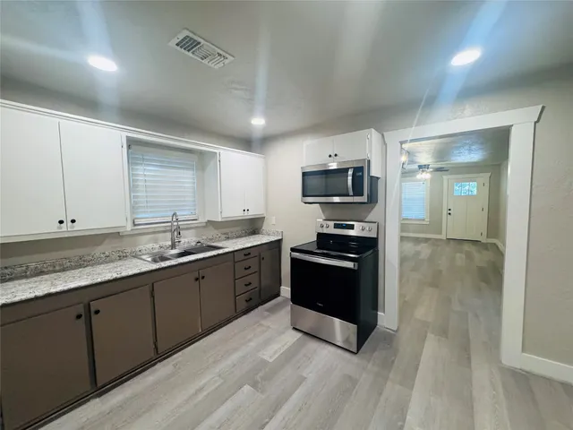 a large kitchen with granite countertop a stove top oven a sink dishwasher a refrigerator and cabinets with wooden floor