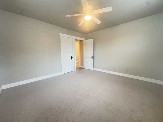 a view of an empty room and chandelier fan