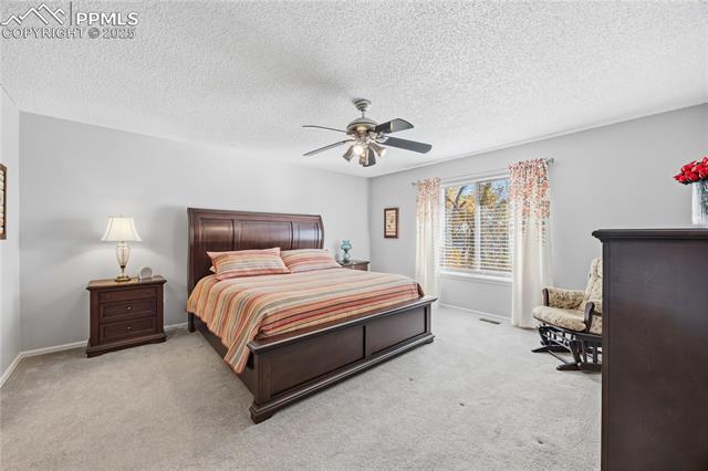 2135 Glenhill Road Colorado Springs, CO 80906 - Photo 19 of 50 Bedroom featuring light colored carpet, a textured ceiling, and ceiling fan