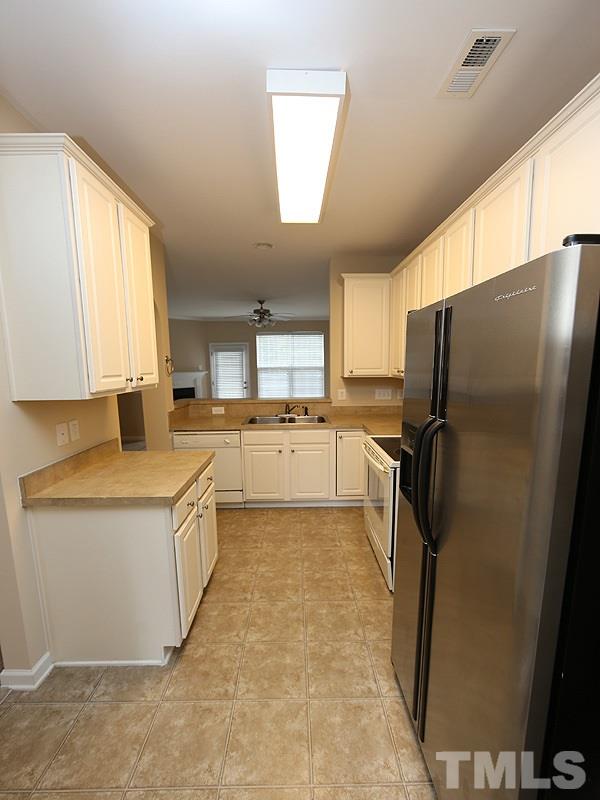 7732 Winners Edge Street Raleigh, NC 27617 - Photo 3 of 12 a kitchen with granite countertop a refrigerator a sink a stove and white cabinets