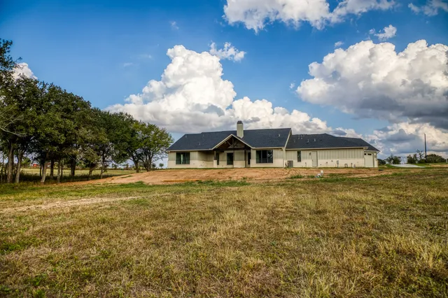 a front view of a house with a garden and trees