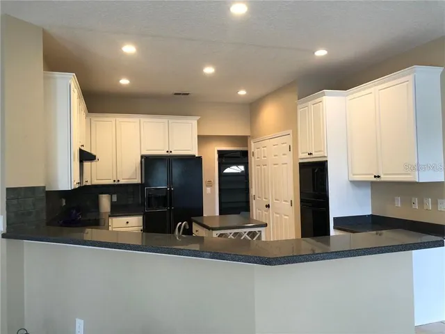 a kitchen with stainless steel appliances granite countertop a sink a stove and a refrigerator