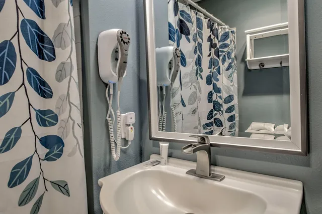 a bathroom with a sink and mirror with bathtub