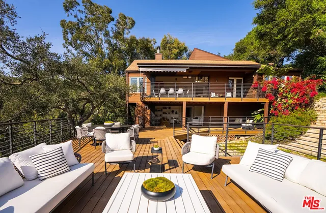 a view of a patio with couches table and chairs with wooden fence and plants