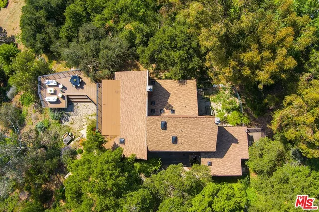 an aerial view of a house with outdoor space and trees all around