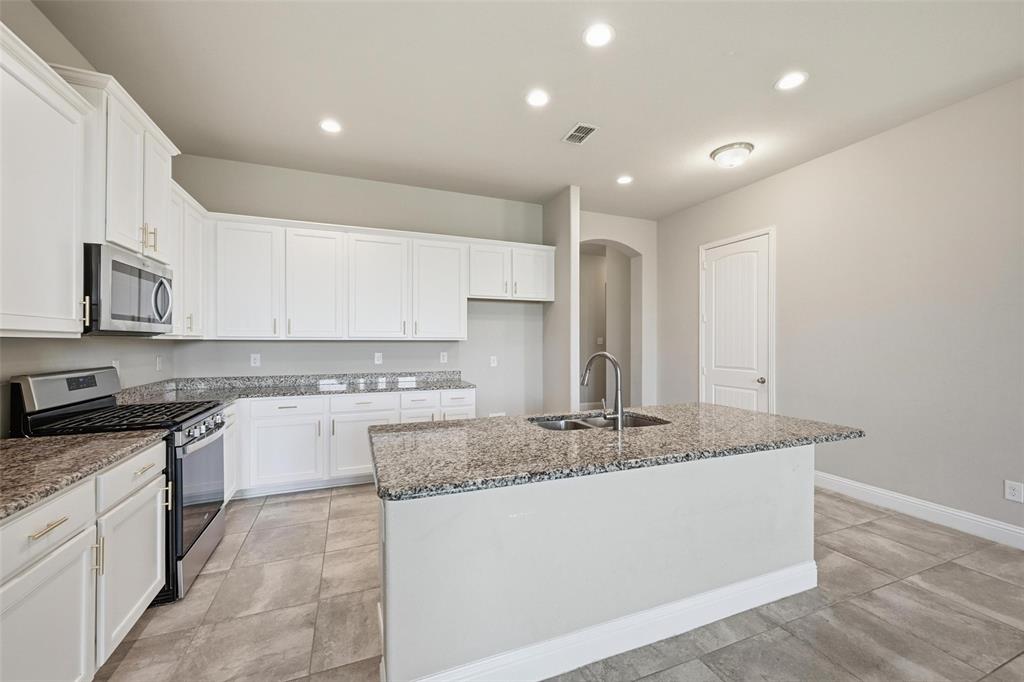2013 Historic District Aubrey, TX 76227 - Photo 4 of 25 a large kitchen with granite countertop a sink and white cabinets