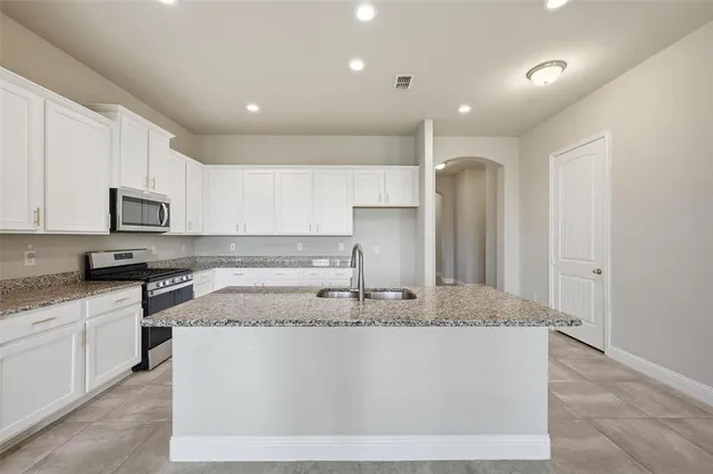 a kitchen with kitchen island granite countertop a sink a counter top space and cabinets