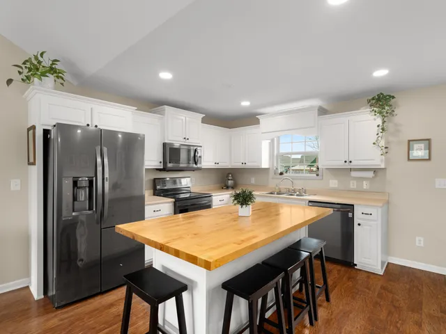 a kitchen with stainless steel appliances granite countertop a stove top oven a refrigerator a sink and a dining table with wooden floor