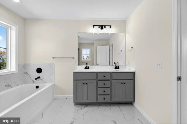 a bathroom with a tub sink double vanity and mirror