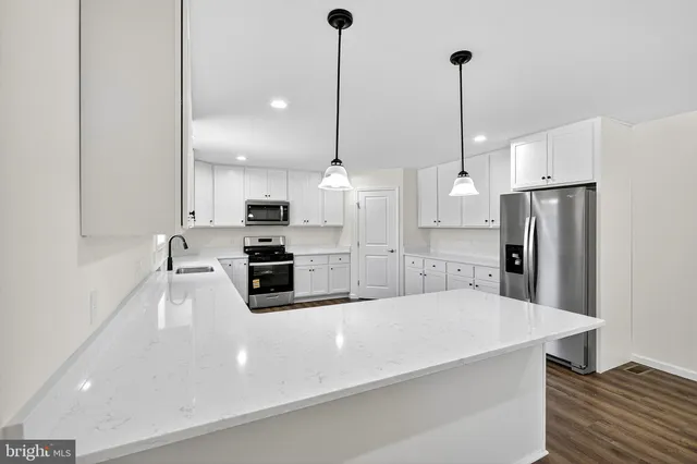 a kitchen with stainless steel appliances kitchen island granite countertop a refrigerator a sink and a stove