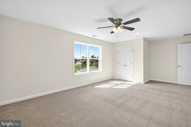 a view of an empty room with a ceiling fan and window