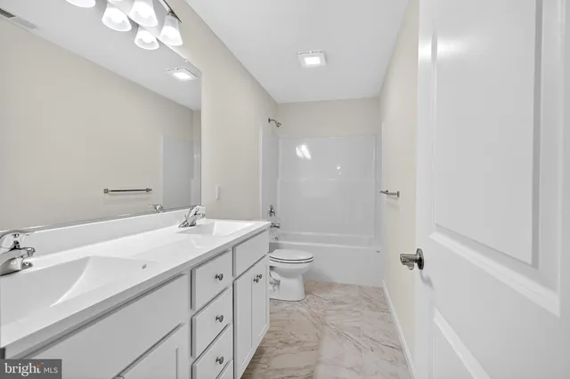 a spacious bathroom with a double vanity sink toilet mirror and bathtub