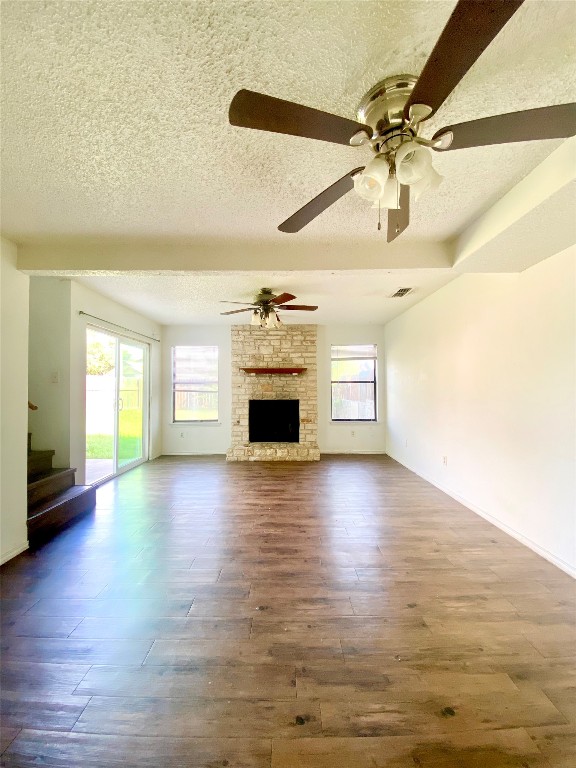 a view of a livingroom with a fireplace a ceiling fan and wooden floor
