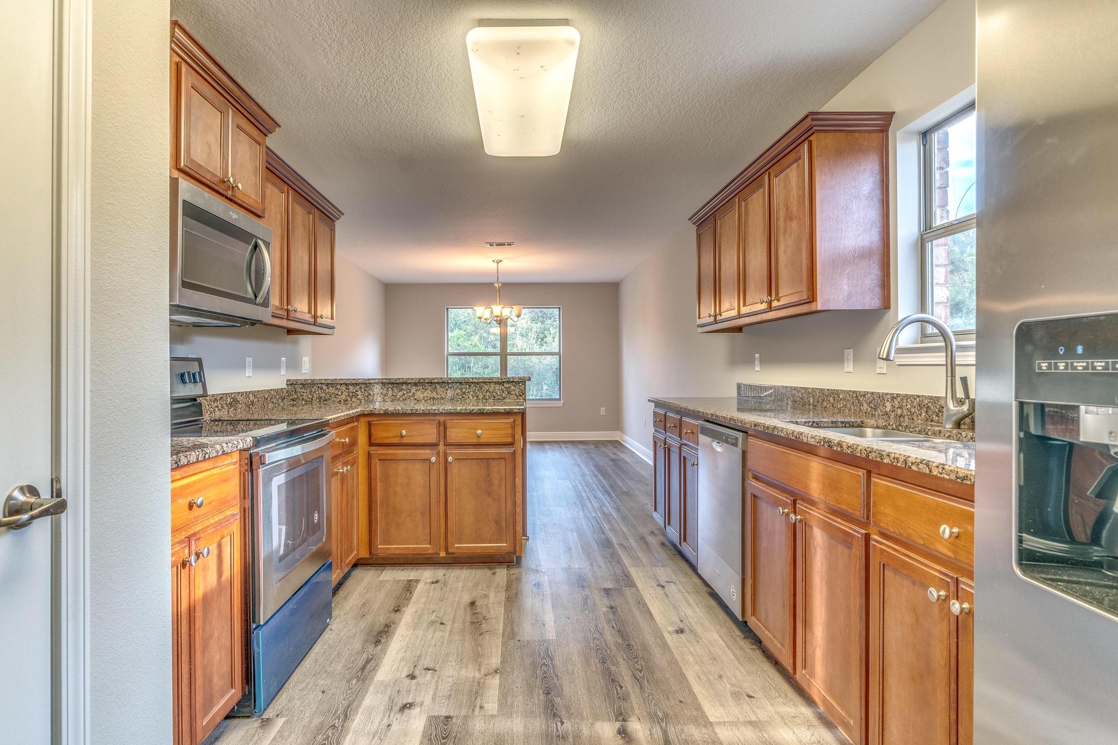 129 Bronze Circle Crestview, FL 32539 - Photo 14 of 31 a kitchen with stainless steel appliances granite countertop a stove a sink and a refrigerator