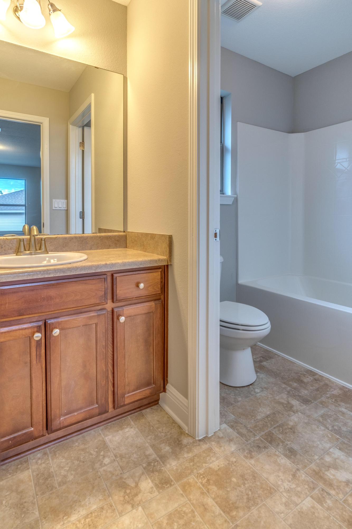 129 Bronze Circle Crestview, FL 32539 - Photo 22 of 31 a spacious bathroom with a granite countertop sink a toilet and a mirror