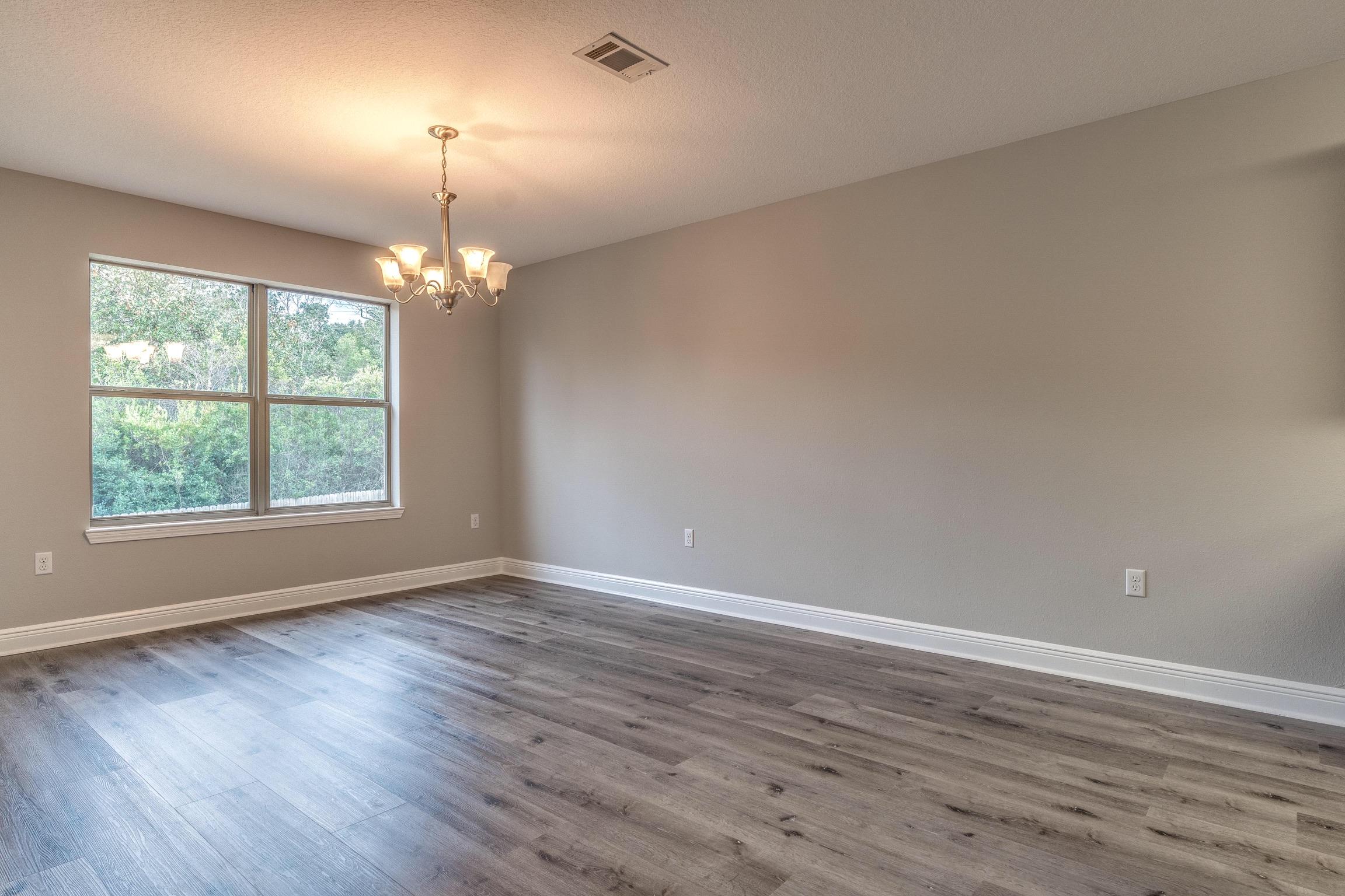 129 Bronze Circle Crestview, FL 32539 - Photo 10 of 31 an empty room with wooden floor chandelier and windows