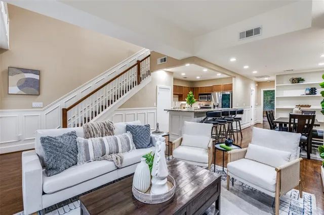 a living room with furniture kitchen view and a wooden floor