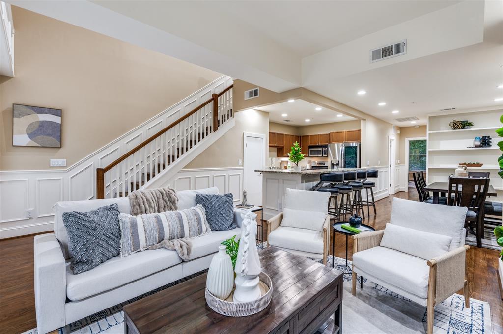 a living room with furniture kitchen view and a wooden floor