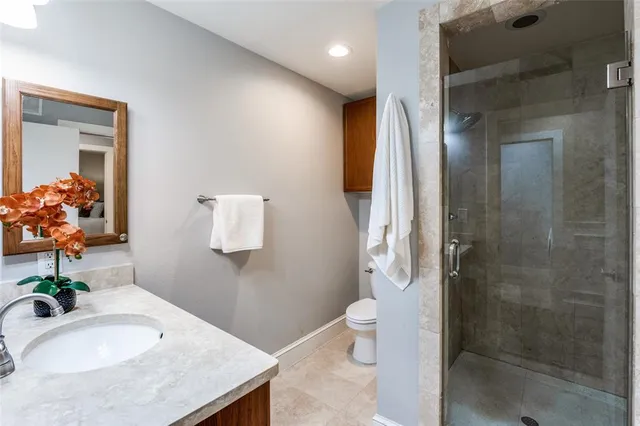 a bathroom with a granite countertop sink a toilet and shower