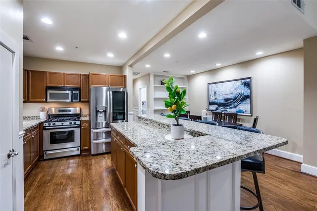a kitchen with stainless steel appliances granite countertop a kitchen island hardwood floor sink stove and refrigerator