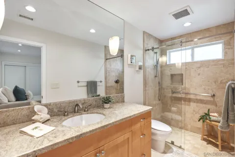 a bathroom with a granite countertop sink mirror vanity and toilet