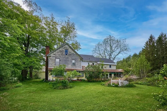 a view of a house with a big yard plants and large trees