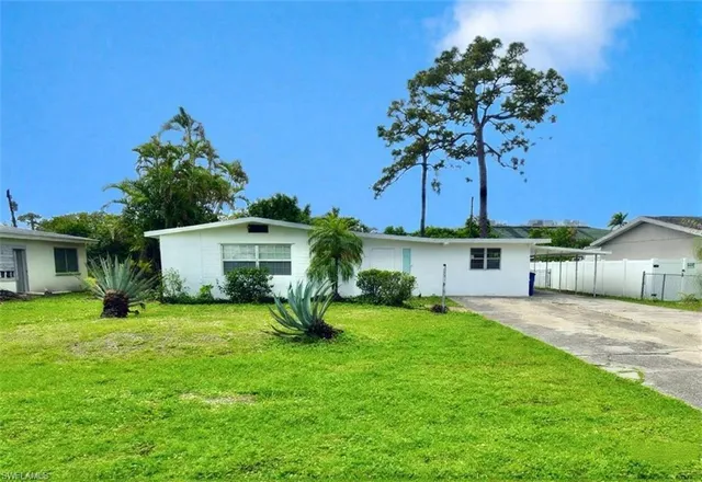 front view of a house with a yard and palm trees