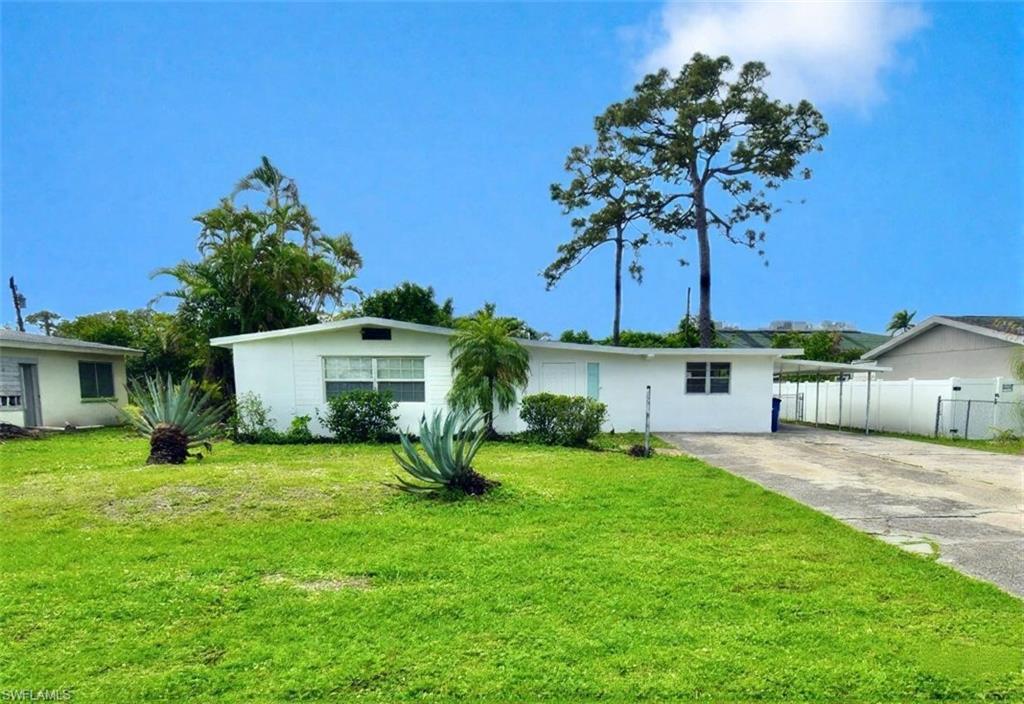 front view of a house with a yard and palm trees