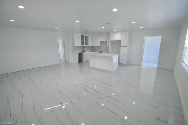 a view of kitchen with kitchen island a sink wooden floor and a refrigerator in it