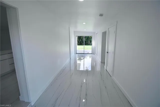 a view of a hallway with wooden floor and a bathroom