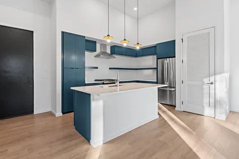 a kitchen with stainless steel appliances a refrigerator and a wooden floor