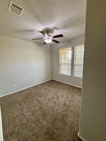 an empty room with windows and fan