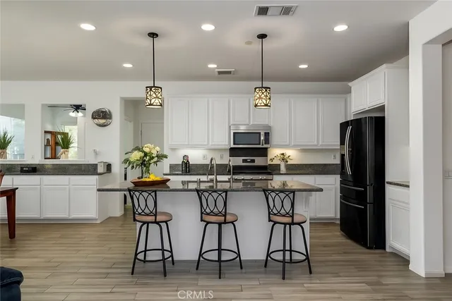 a kitchen with stainless steel appliances kitchen island granite countertop a table chairs stove and microwave