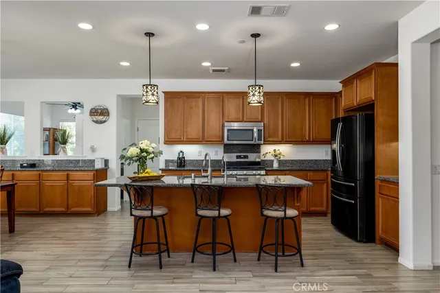 a kitchen with stainless steel appliances granite countertop a table chairs refrigerator and sink