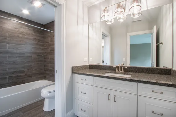 a bathroom with a granite countertop sink a toilet and bathtub