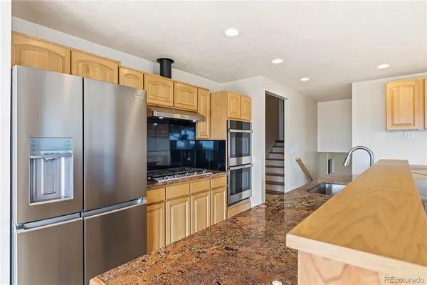 a kitchen with stainless steel appliances granite countertop a refrigerator and a sink