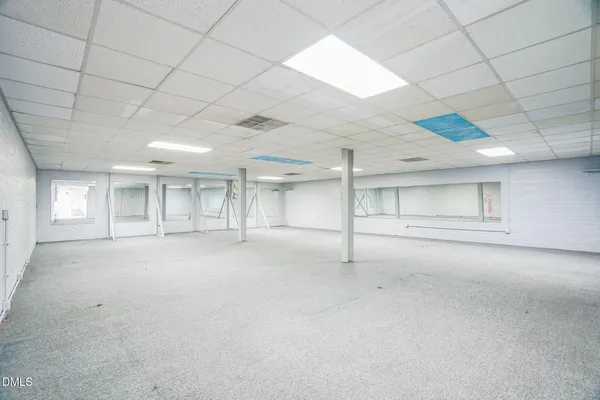 an empty room with chandelier fan and windows
