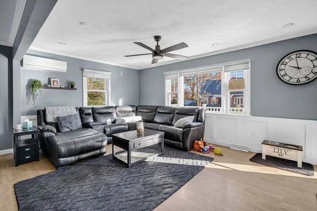 a living room with furniture a clock on wall and a window