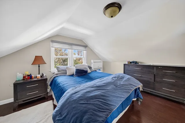a bedroom with a bed and dresser with wooden floor