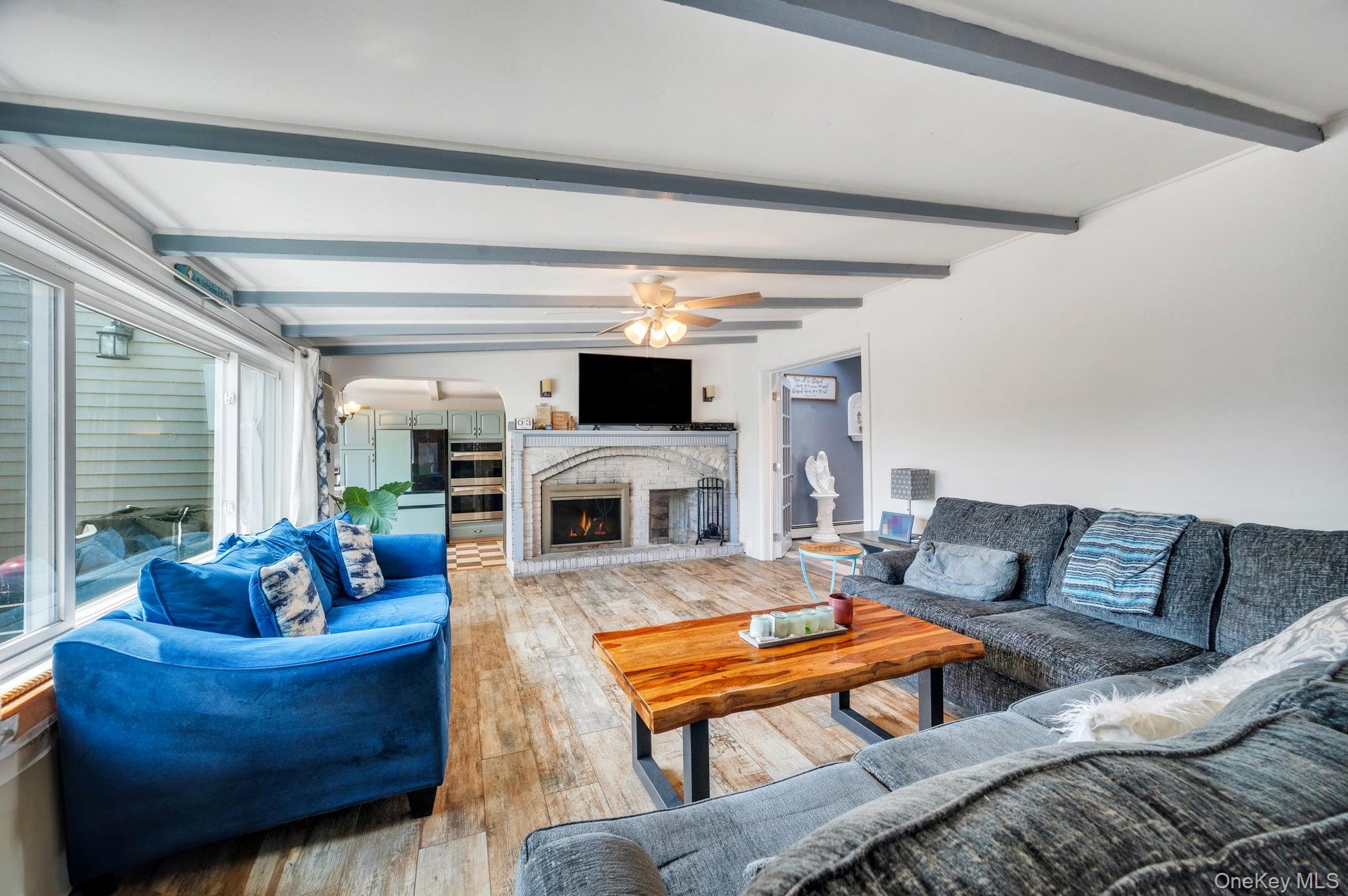 24 Raynor Street West Babylon, NY 11704 - Photo 14 of 45 Living area with light wood-style flooring, beam ceiling, arched walkways, and a fireplace