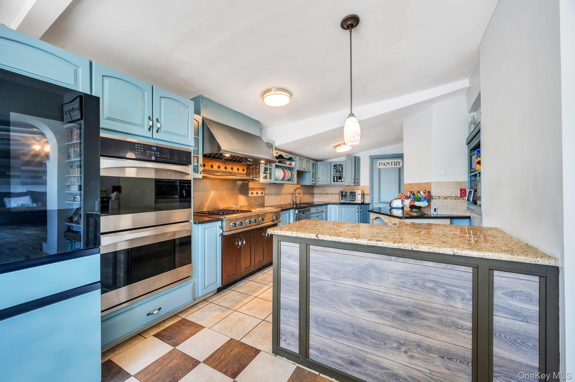 24 Raynor Street West Babylon, NY 11704 - Photo 28 of 45 Kitchen featuring decorative backsplash, blue cabinetry, stainless steel appliances, decorative light fixtures, and vaulted ceiling