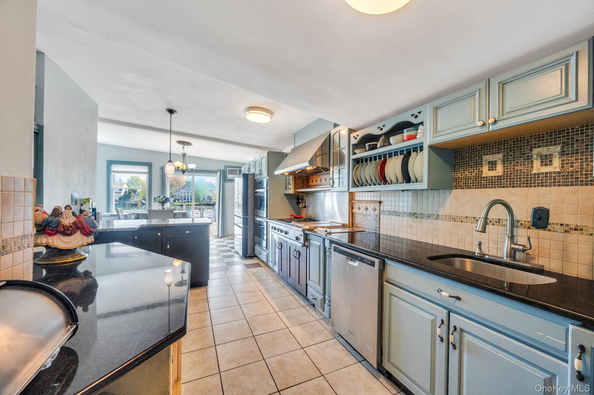 24 Raynor Street West Babylon, NY 11704 - Photo 29 of 45 Kitchen featuring decorative backsplash, light tile patterned flooring, dark stone countertops, appliances with stainless steel finishes, and decorative light fixtures