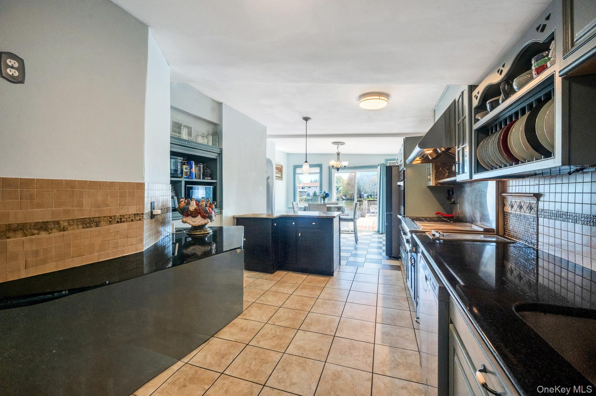 24 Raynor Street West Babylon, NY 11704 - Photo 30 of 45 Kitchen with backsplash, dark cabinets, decorative light fixtures, and light tile patterned floors