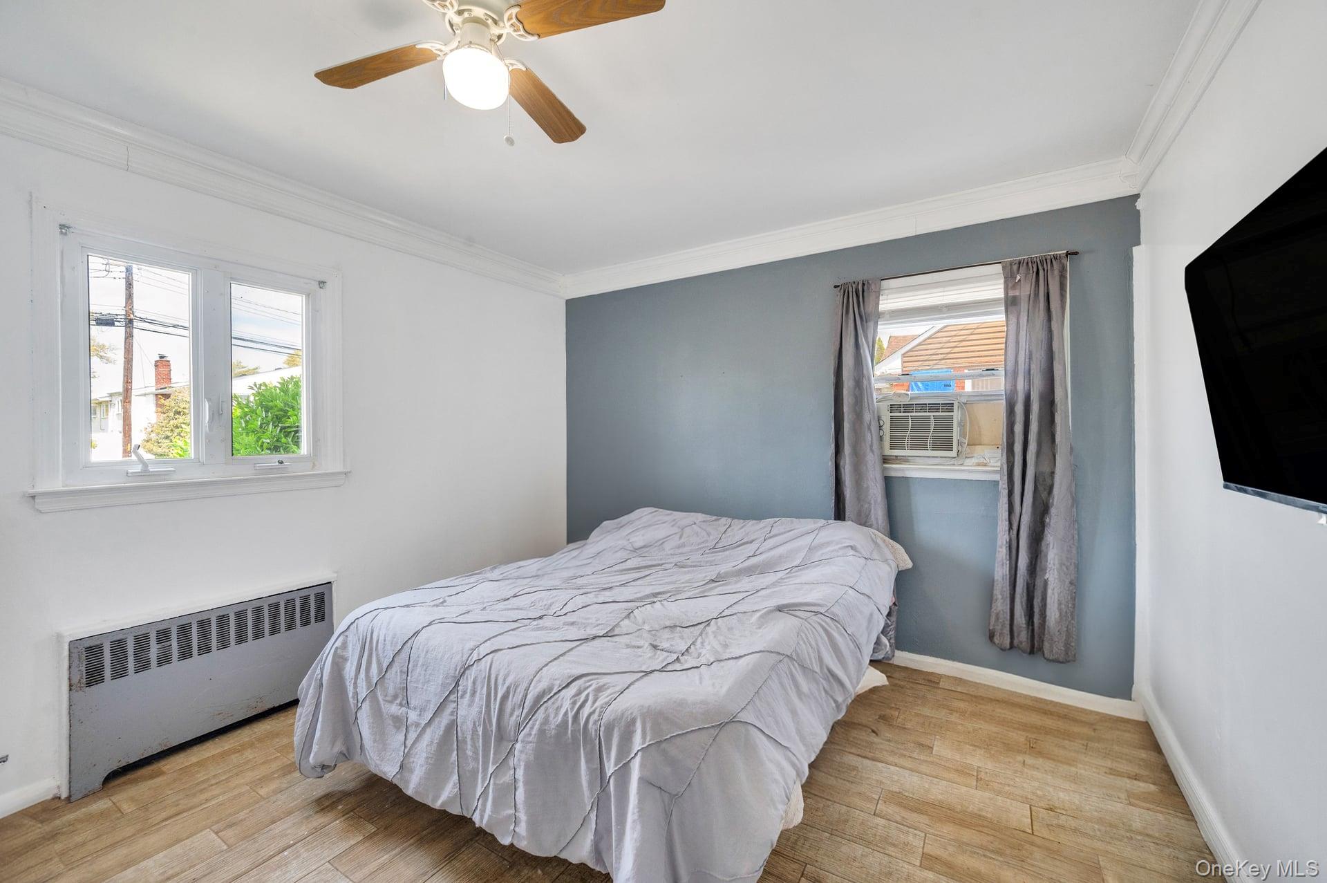 24 Raynor Street West Babylon, NY 11704 - Photo 35 of 45 Bedroom featuring radiator heating unit, wood finished floors, crown molding, and a ceiling fan