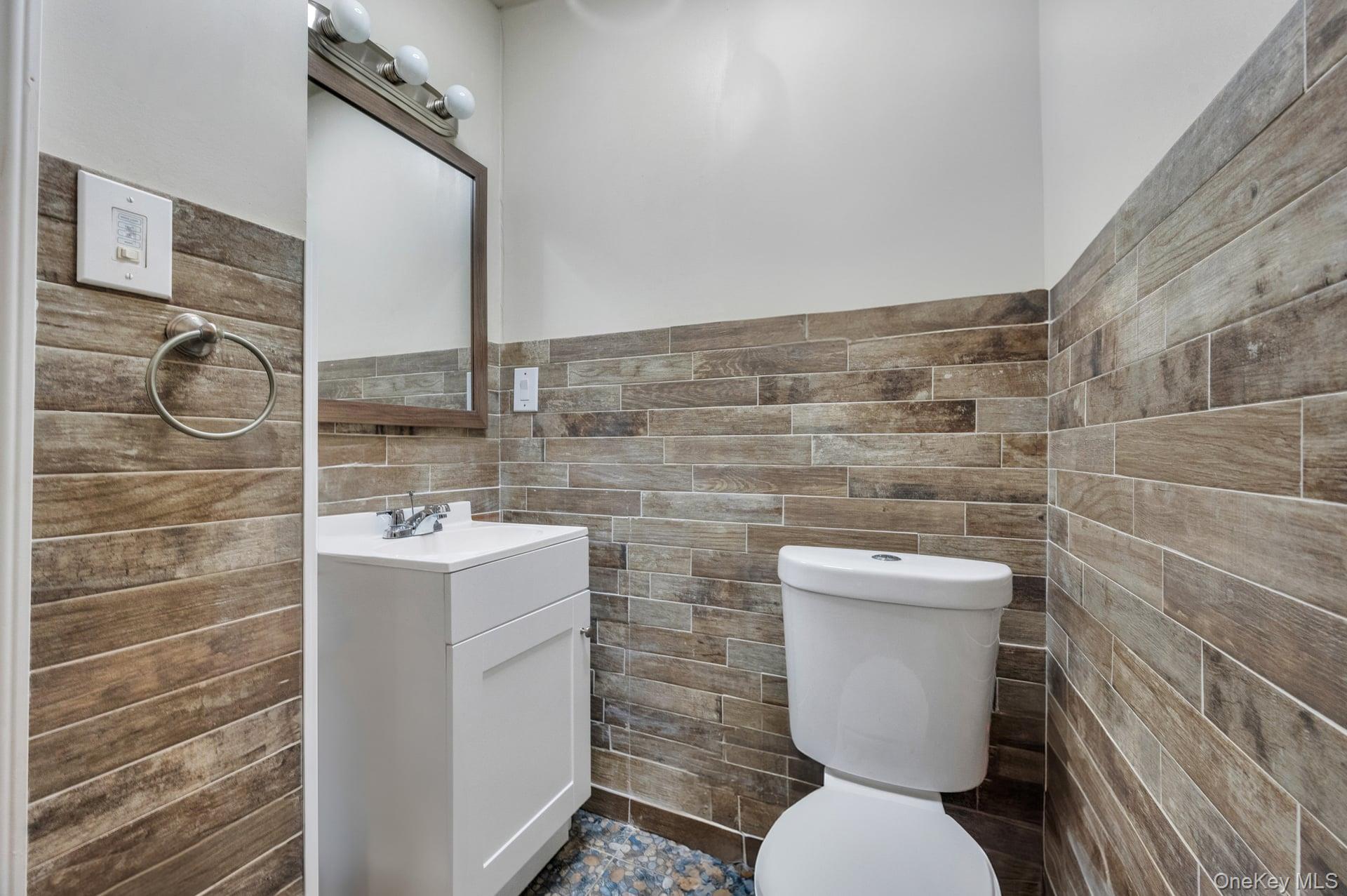 24 Raynor Street West Babylon, NY 11704 - Photo 36 of 45 Half bathroom featuring vanity, tile walls, and a wainscoted wall